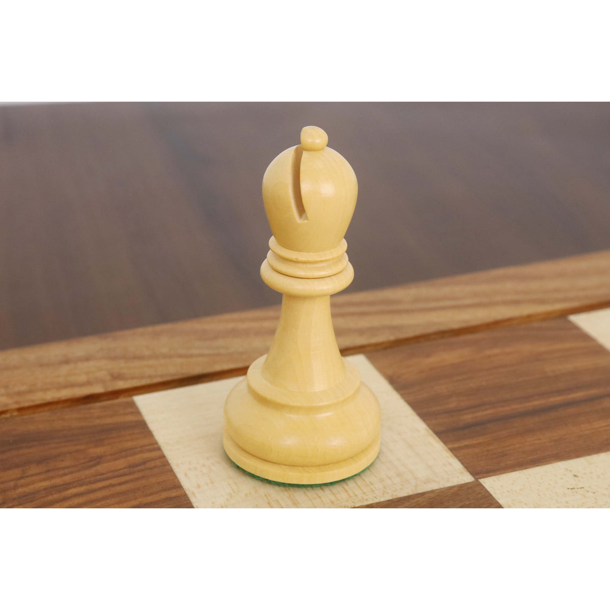 Elegant light Staunton bishop chess piece displayed on a wooden chessboard.