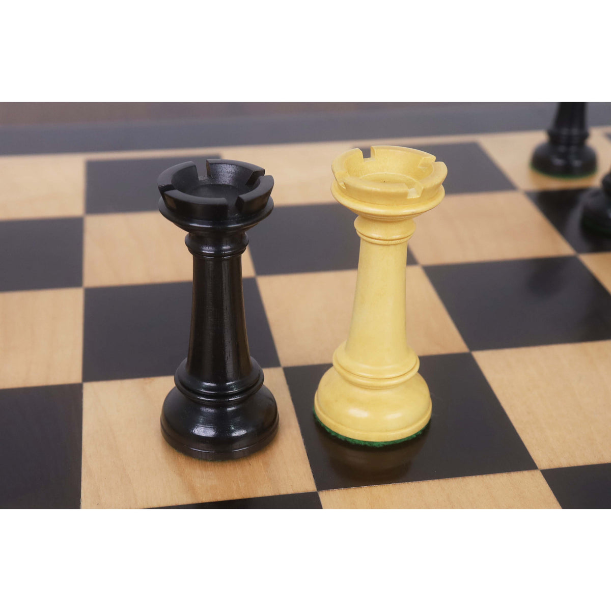 Ebony and boxwood rook chess pieces displayed on a wooden chessboard.