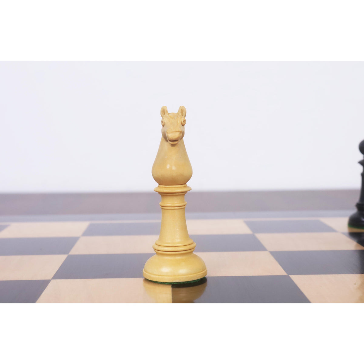 Front-facing view of a carved boxwood knight chess piece on a board.