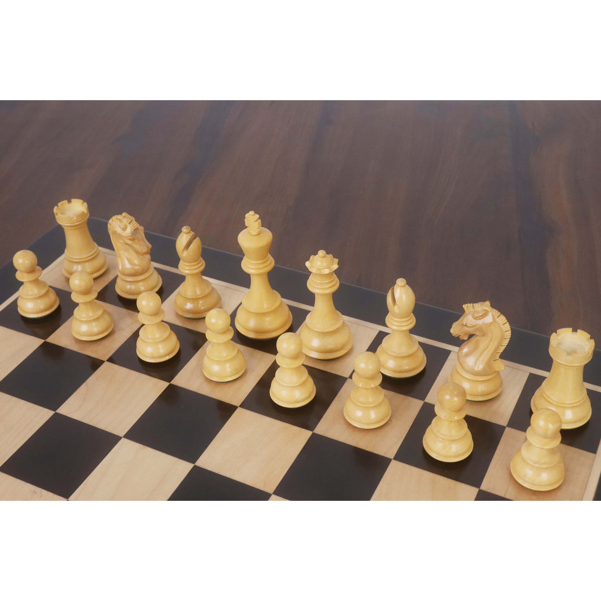Ivory boxwood Staunton chess pieces set up on a wooden chessboard.