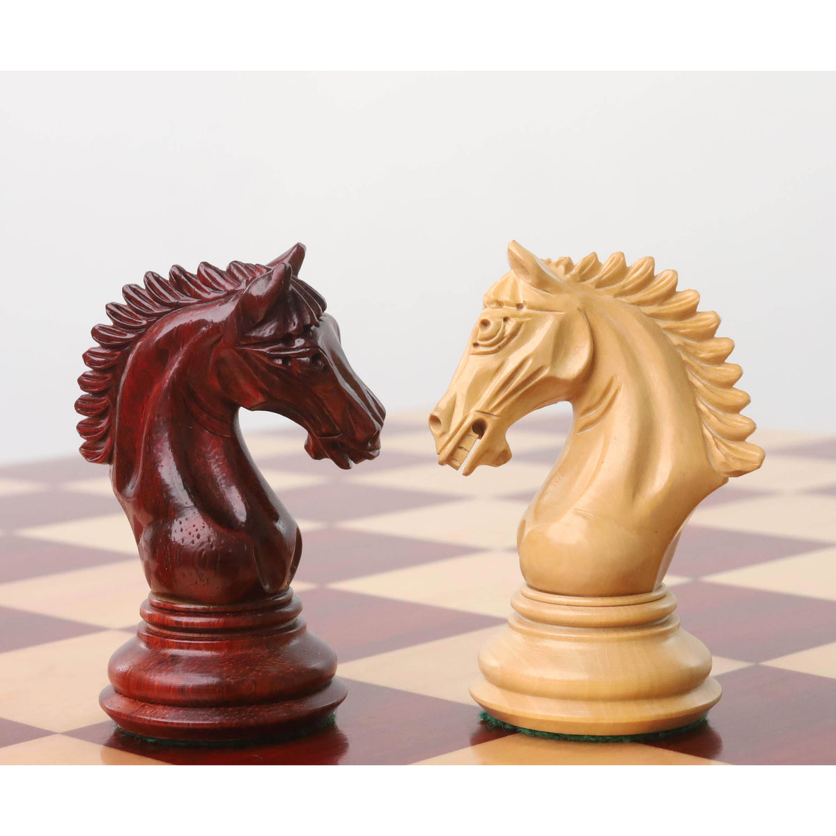 Close-up of two Staunton chess knights facing off on a luxury chessboard.