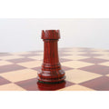 Dark Bud Rosewood Staunton rook standing on a wooden chessboard.