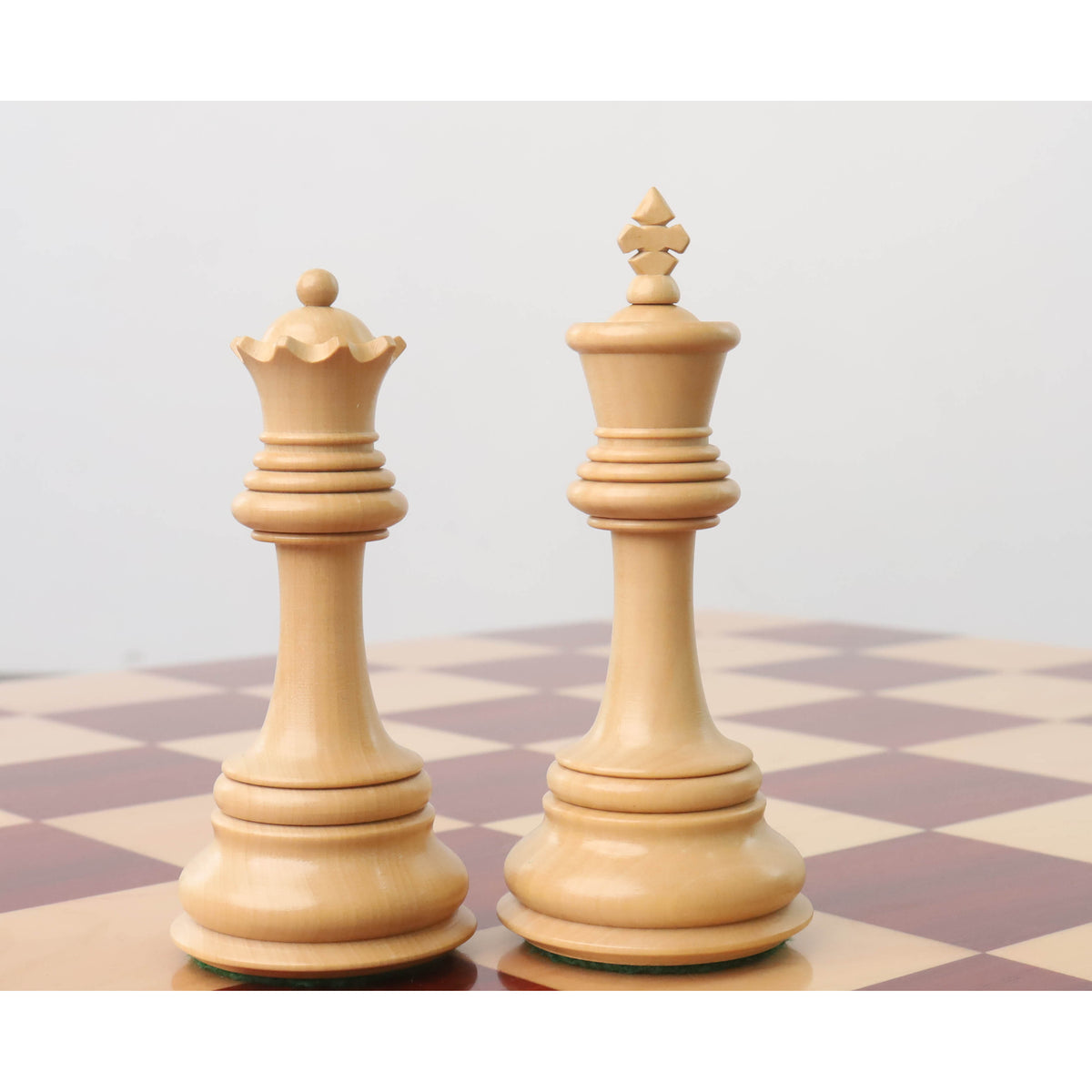 Light Boxwood Staunton king and queen pieces displayed on a wooden chessboard.