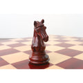 Hand-carved dark Bud Rosewood Staunton knight on a wooden chessboard.