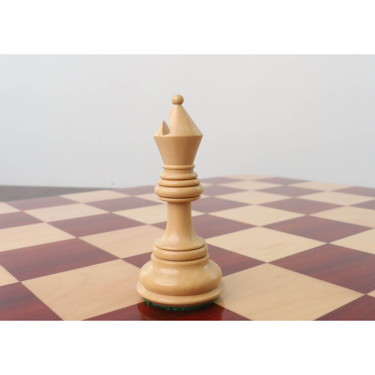 Light Boxwood Staunton bishop standing on a wooden chessboard.