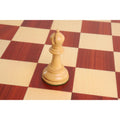 Hand-carved boxwood bishop chess piece standing on a wooden board.