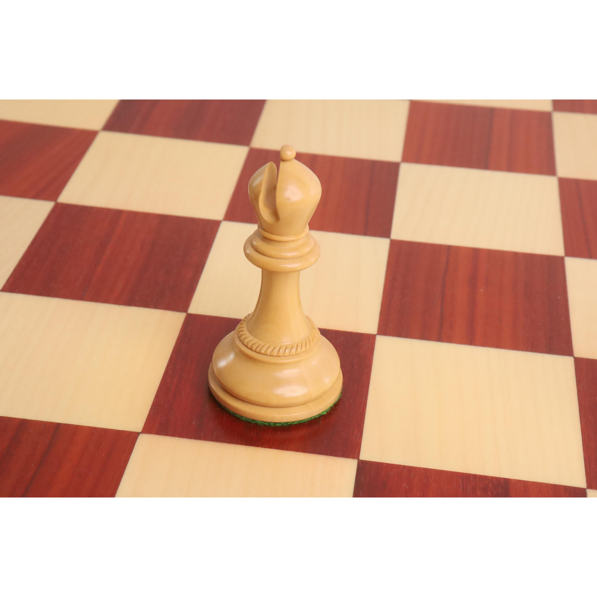 Hand-carved boxwood bishop chess piece standing on a wooden board.