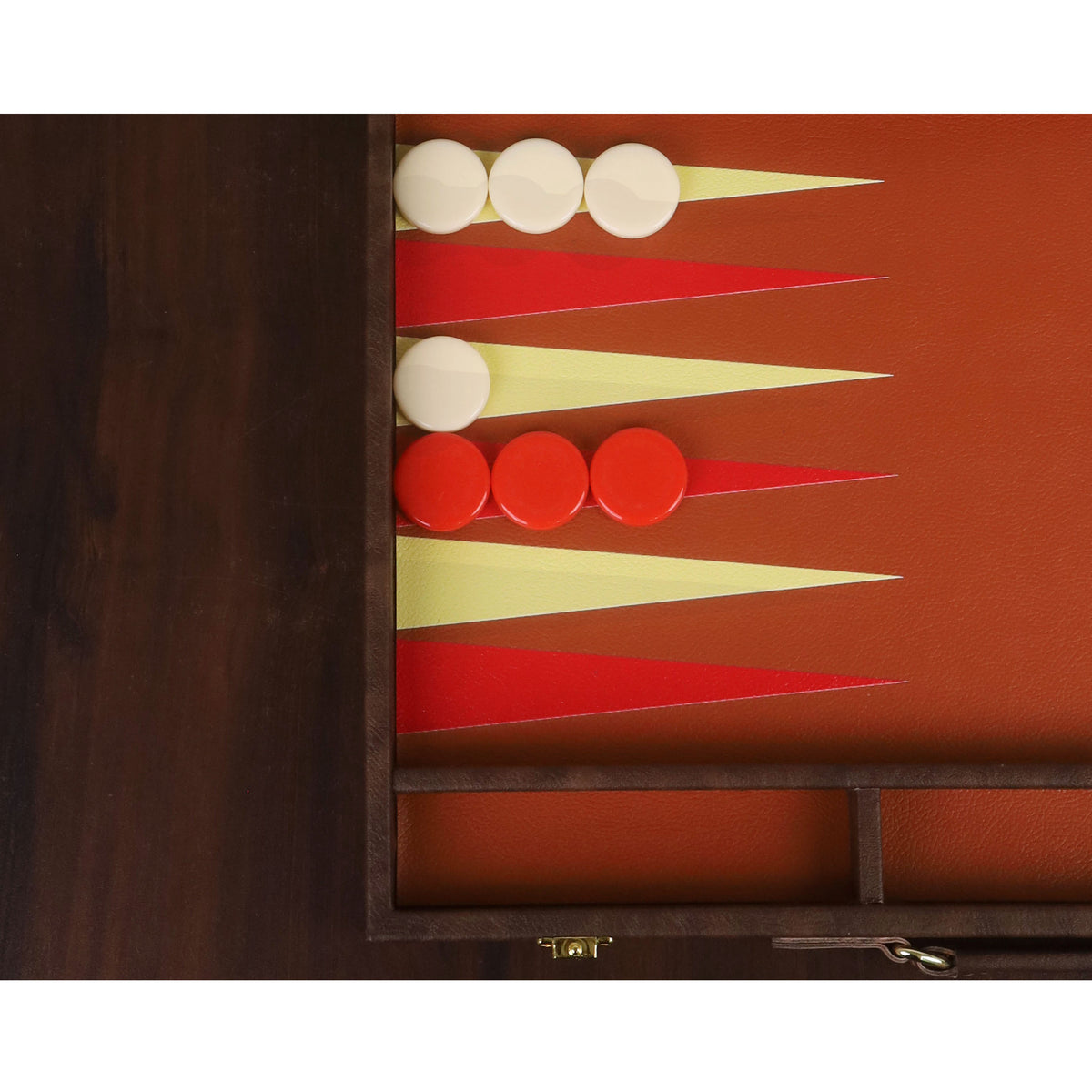 Cream and red backgammon checkers aligned on textured points of a luxury leatherette board.