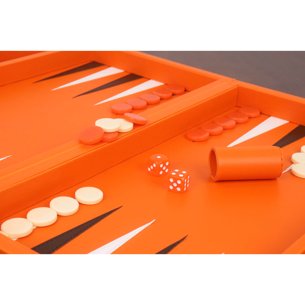 Detailed view of orange dice and cream checkers on a high-quality leatherette backgammon playing field.
