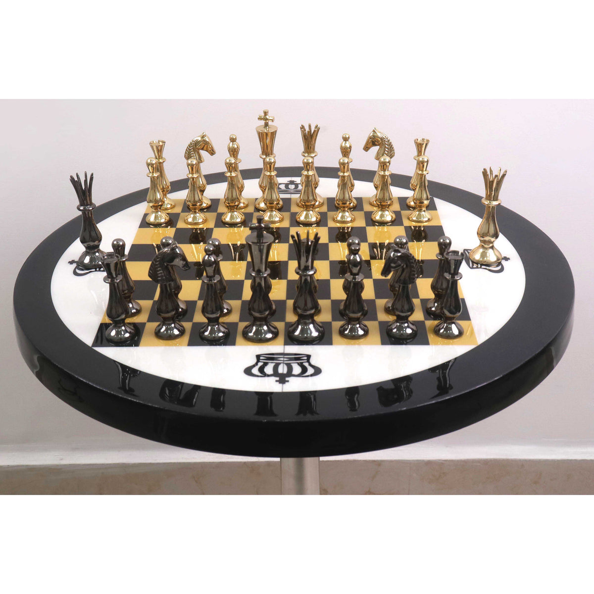 Reflective gold and black minimalist brass chess pieces arranged on a glossy checkered board.
