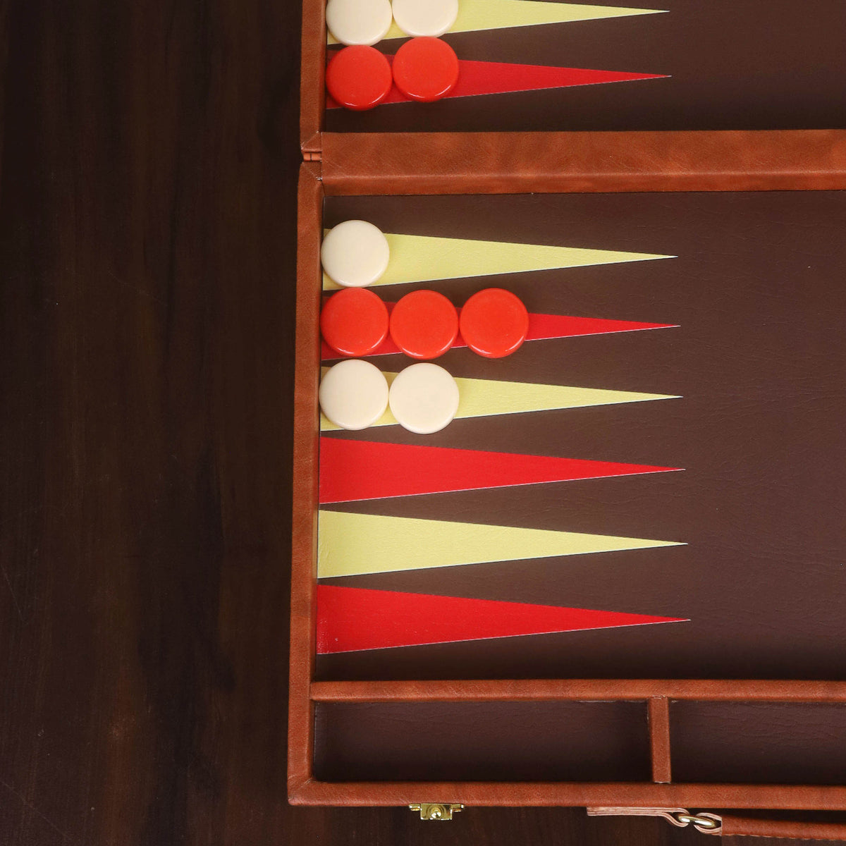 Close-up of the premium cognac brown leatherette texture and vibrant red and cream backgammon checkers.