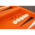 Close-up of cream and orange backgammon checkers on black and white stitched leatherette triangular pips.