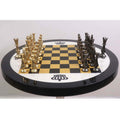 Perspective view of gold and black nickel minimalist chess pieces facing off on a luxury table set.