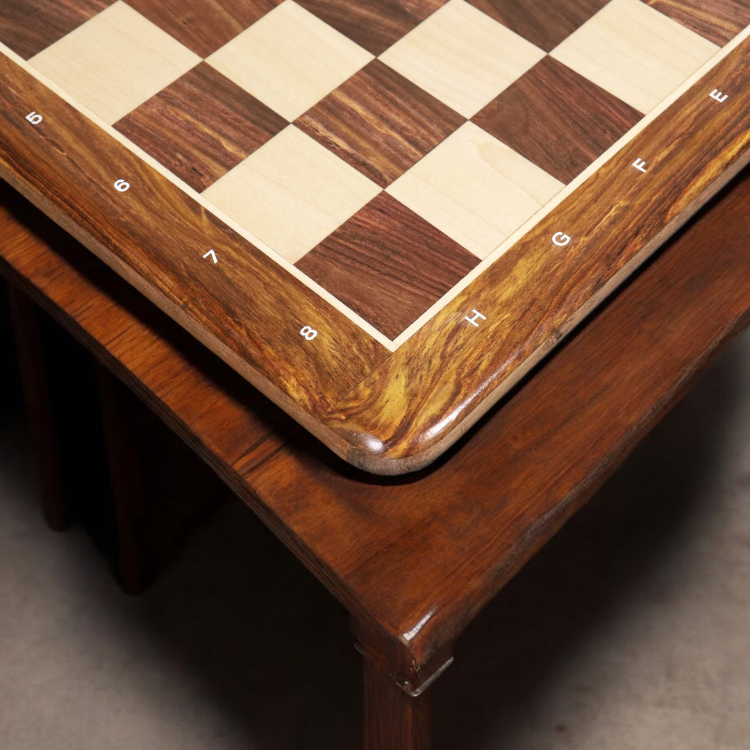 Close-up of a premium golden rosewood chess board corner displayed on a dark wooden furniture surface.