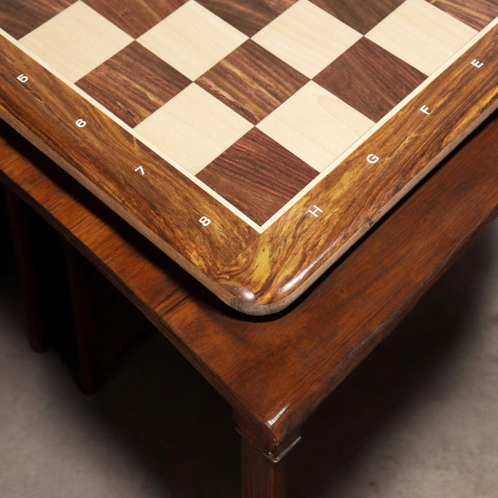 Close-up of a premium golden rosewood chess board corner displayed on a dark wooden furniture surface.