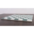 Low-angle side profile of a slim borderless malachite stone chess board on a dark surface.