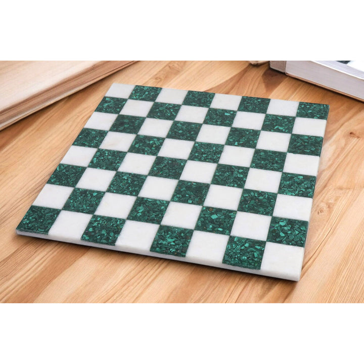 Green malachite and white semi-precious stone chess board displayed on a wooden tabletop.