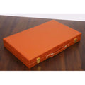 Closed rich brown leatherette backgammon briefcase with gold-tone latches on a dark wood table.