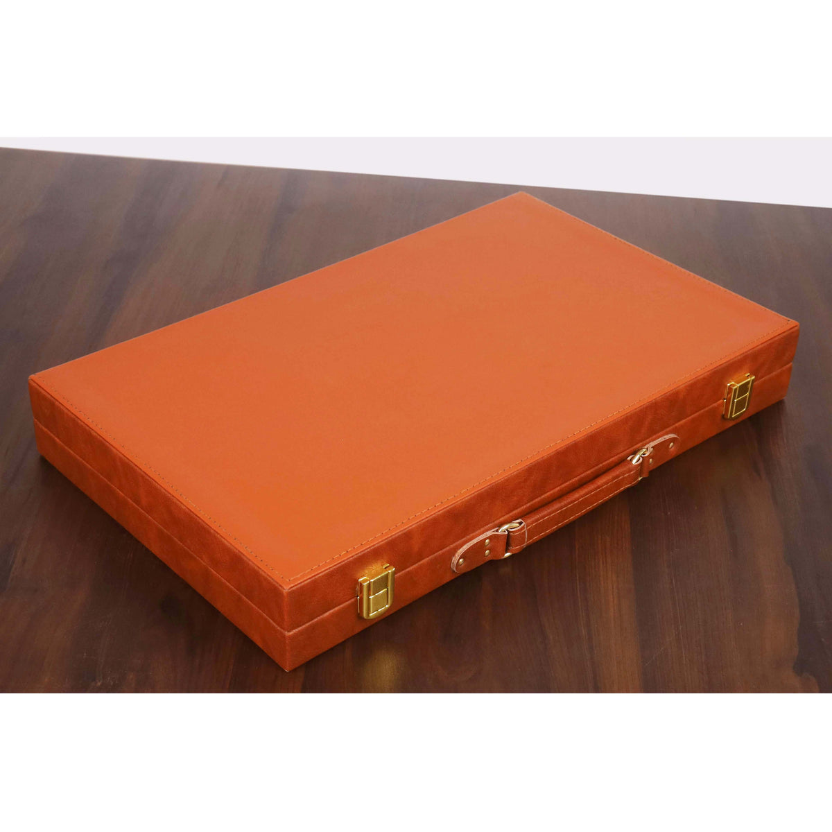 Closed rich brown leatherette backgammon briefcase with gold-tone latches on a dark wood table.