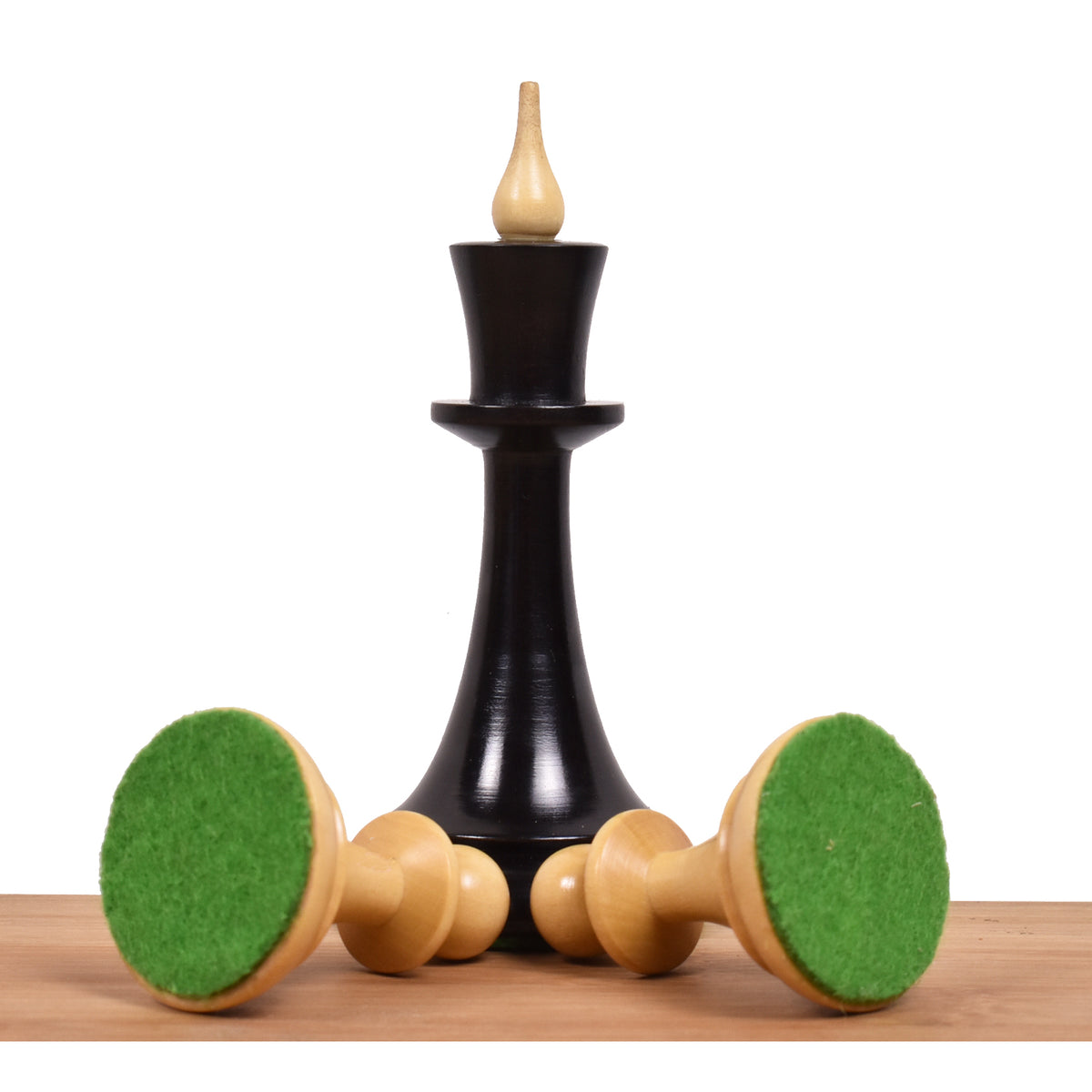 Ebonised boxwood King piece standing with boxwood pawns tilted to show green felted bases.