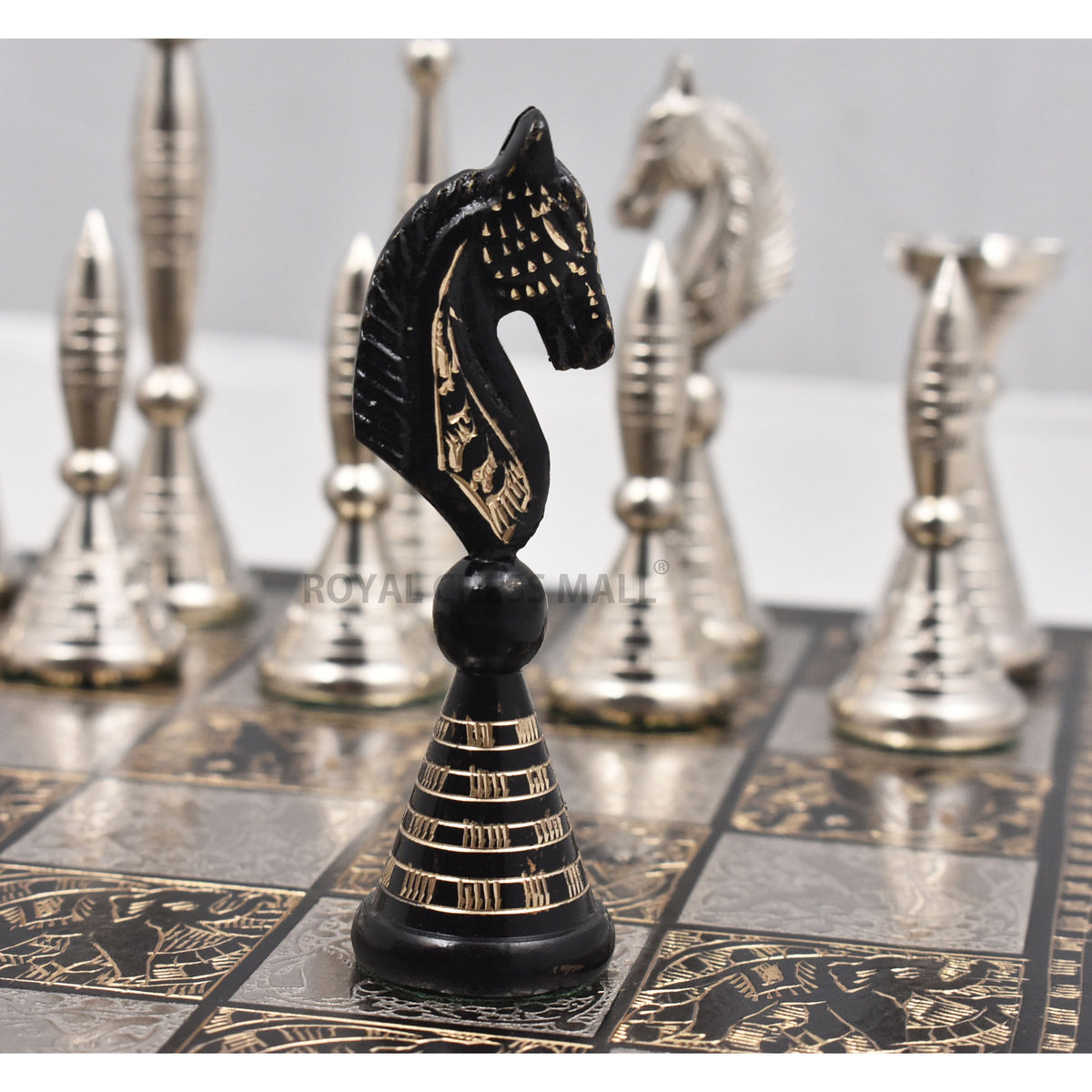 Close-up of the black brass Warli artwork knight chess piece with soft background.