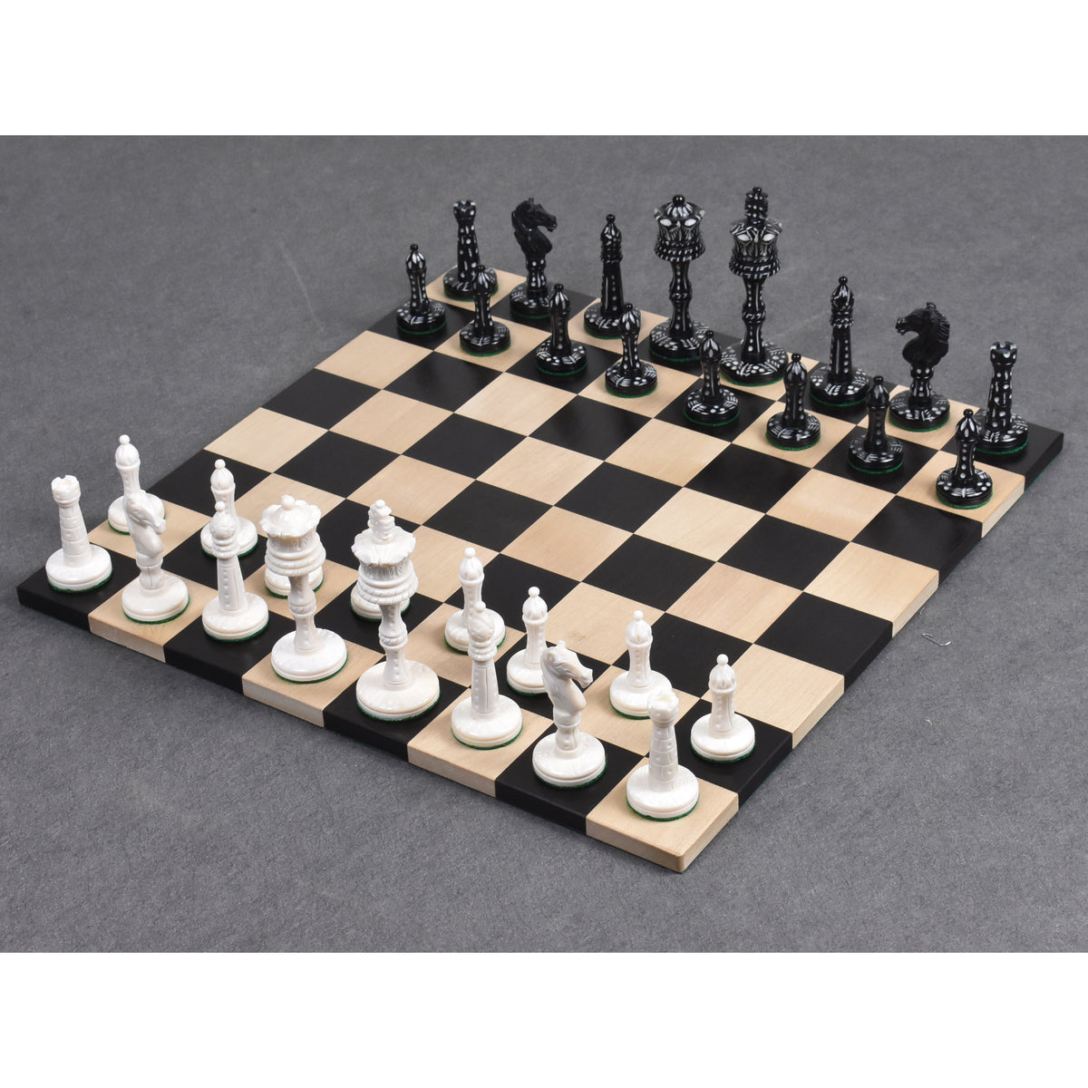 Complete set of white and black camel bone Victorian era pre-Staunton chess pieces set up for play on a wooden board.