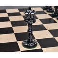 Intricately carved black camel bone Victorian era pre-Staunton queen piece placed on a wooden chessboard.