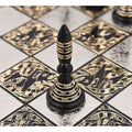 Detailed view of a black solid brass Warli art pawn piece on a metal chess board.