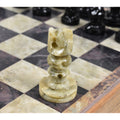 Detailed close-up of a handcarved soapstone knight chess piece on a polished stone board.