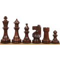 Six dark Anjan rosewood Pinney Staunton chess pieces standing in a row from King to pawn.