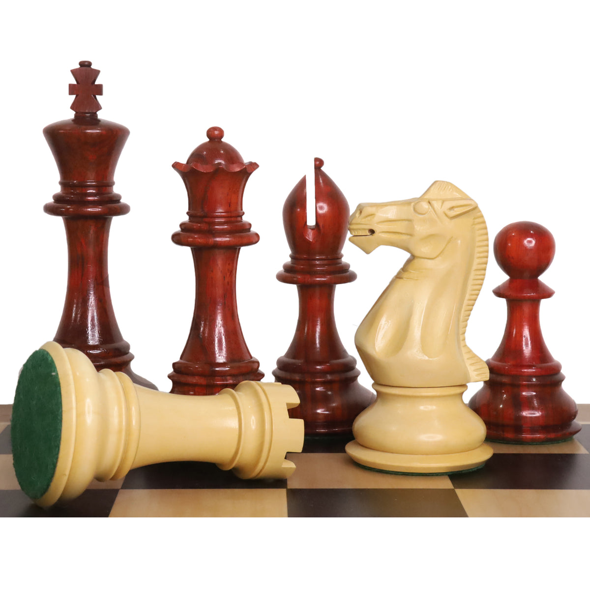 Bud rosewood luxury Staunton chess pieces lined up on a board with a boxwood rook showing its green felt base.