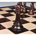 Dark rosewood Majestic Staunton queen on a wooden board, featuring a crisp crown detail against a blurred background.
