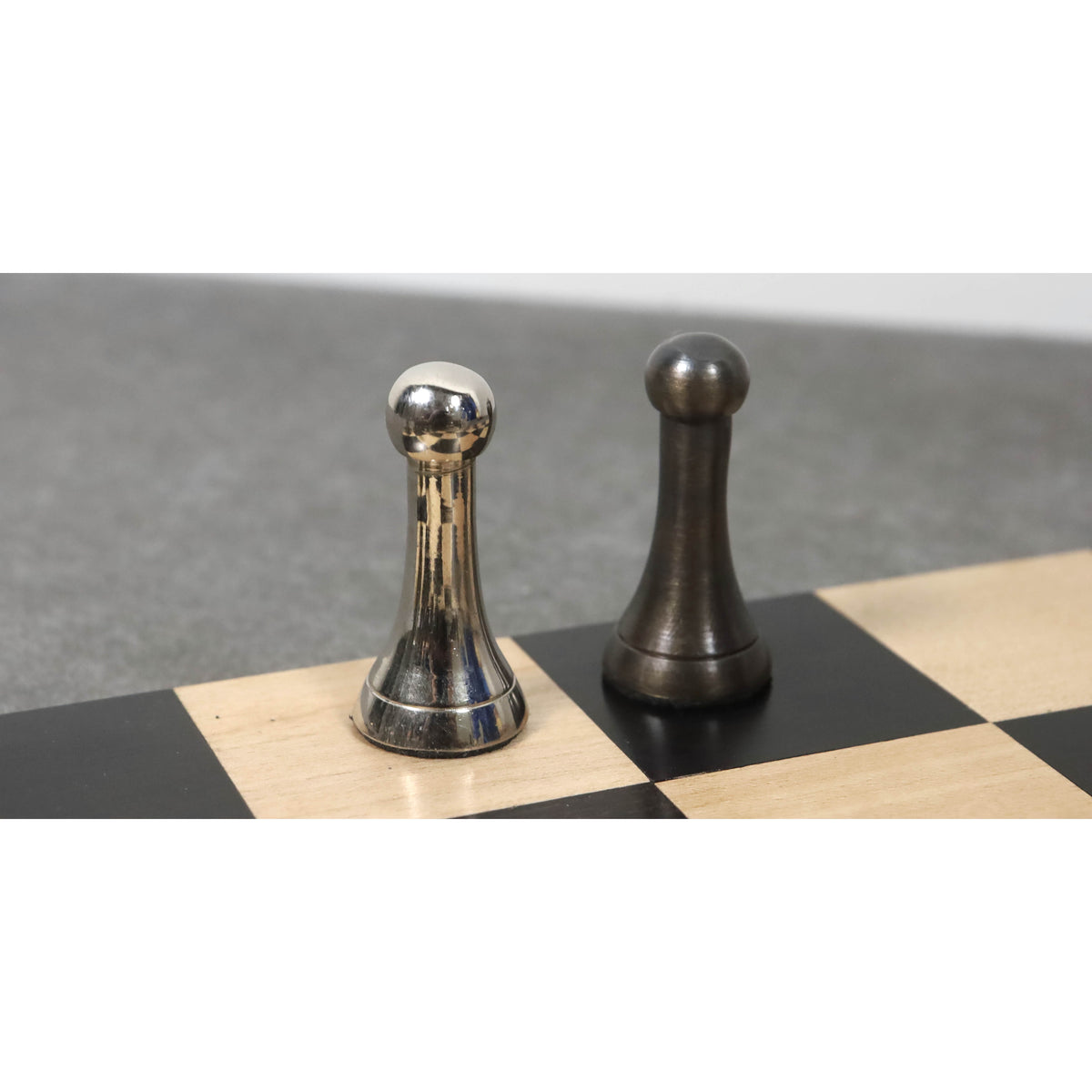 Comparison of contemporary luxury brass chess pawns in silver and antique metal finishes.