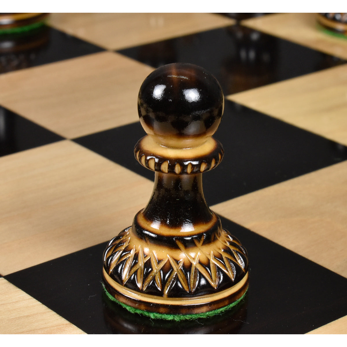 Burnt lacquer finish boxwood pawn from the Parker Staunton chess set on a glossy board.