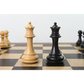 White and black Pro Staunton queen chess pieces placed on a wooden board.