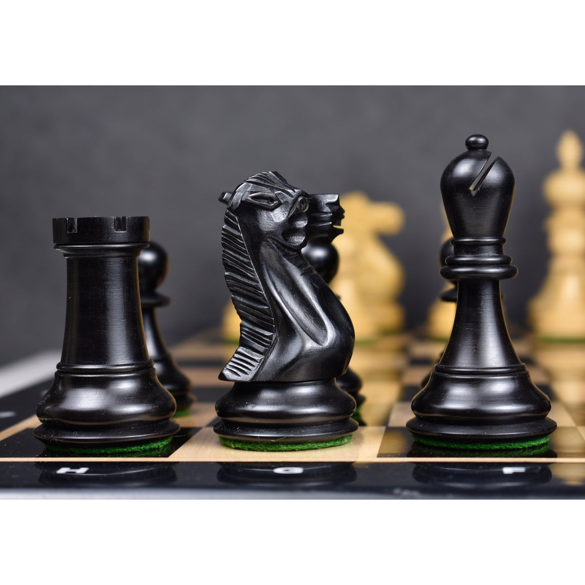 Black Executive Staunton knight and bishop pieces on a chessboard.