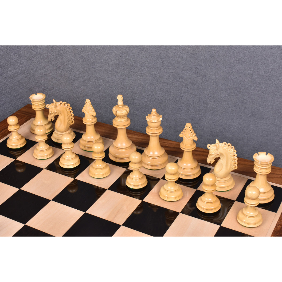 Complete army of boxwood Carvers Art chess pieces set up on a glossy wooden board.