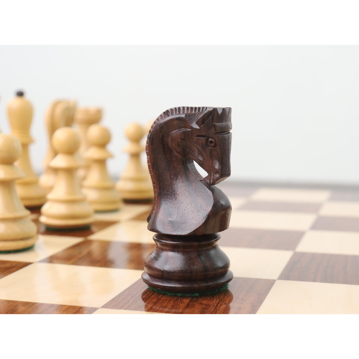 Finely carved dark rosewood Zagreb knight chess piece showcased on a wooden board.