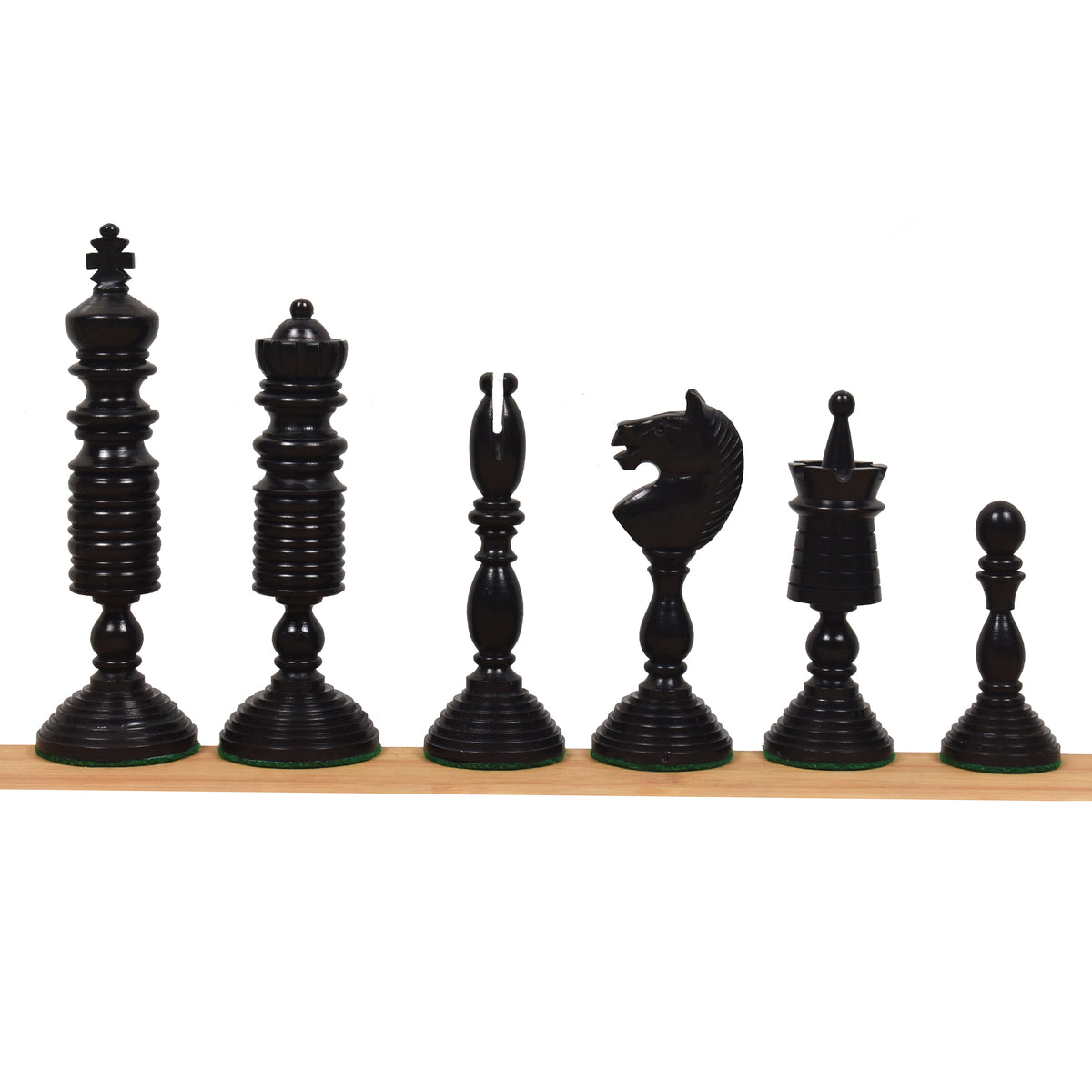 Dark antique pre-Staunton chess pieces arranged on a wooden surface.