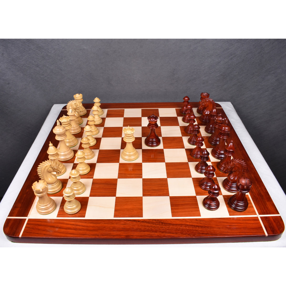 Overhead layout view of 4.4 inch Dragon Staunton luxury chess pieces on a large bordered wooden chessboard.