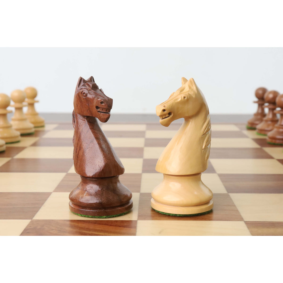 Golden rosewood and boxwood French Grandmaster knight pieces facing off.