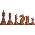 Golden rosewood French Grandmaster chess pieces lined up on a shelf.