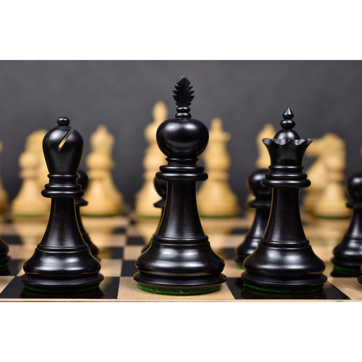 Black Executive Staunton king, queen, and bishop on a chessboard.