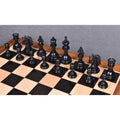 Full set of triple-weighted ebony wood chess pieces standing in formation on a board.