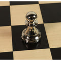 Reflective silver brass metal luxury chess piece pawn showcasing high-gloss metallic polish on a board.