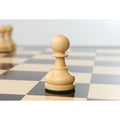 Single natural boxwood pawn piece highlighted on a glossy tournament chessboard.