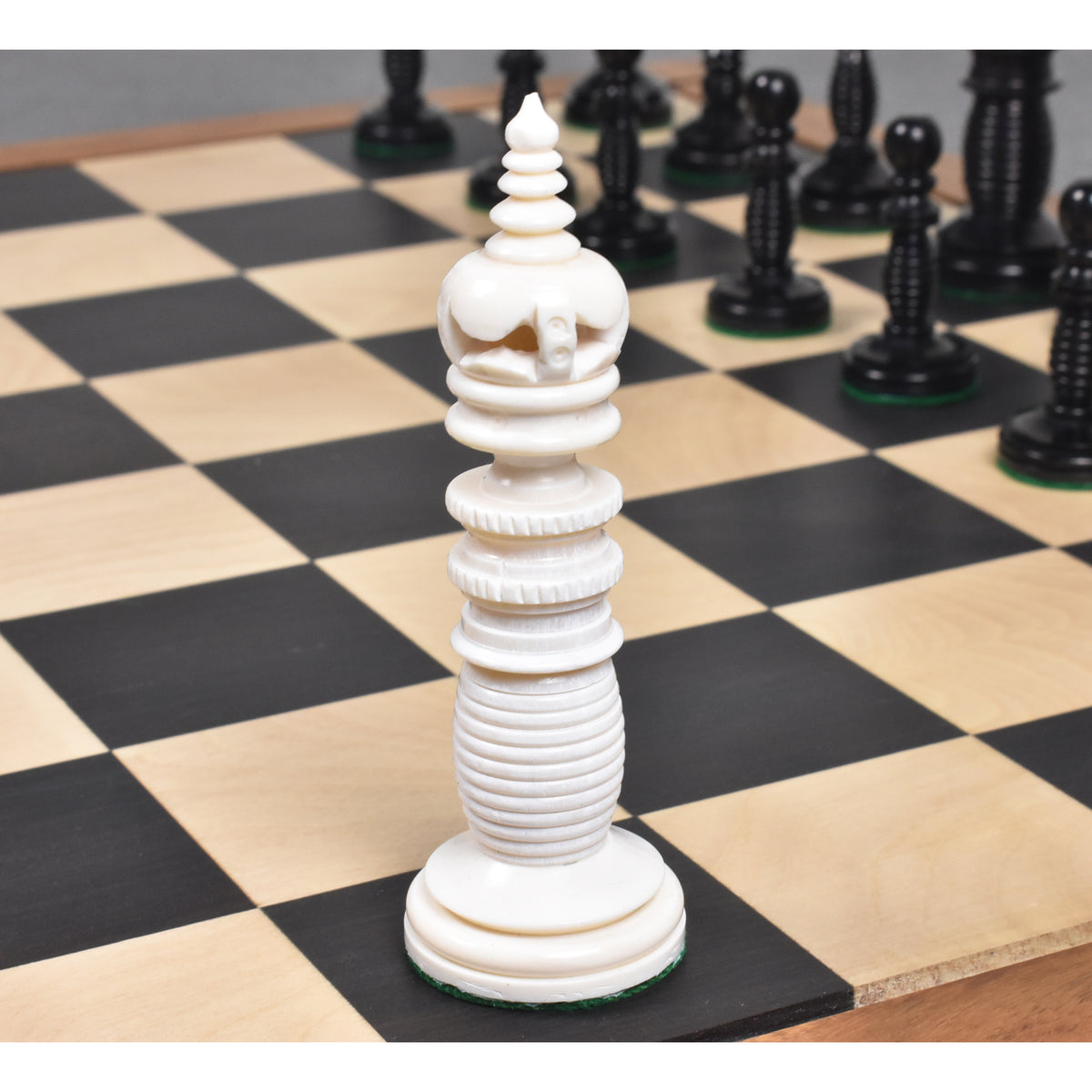 Minaret series ivory white camel bone queen chess piece with tiered finial on a wooden board.