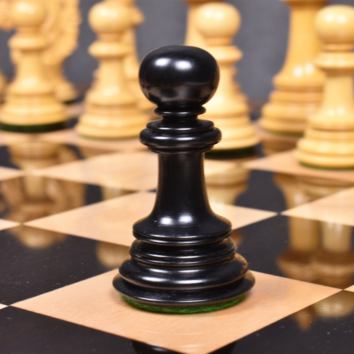 Black ebony wood Mogul Staunton pawn piece on a luxury chessboard.