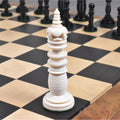 Hand-carved camel bone queen chess piece in ivory white standing on a checkered board.