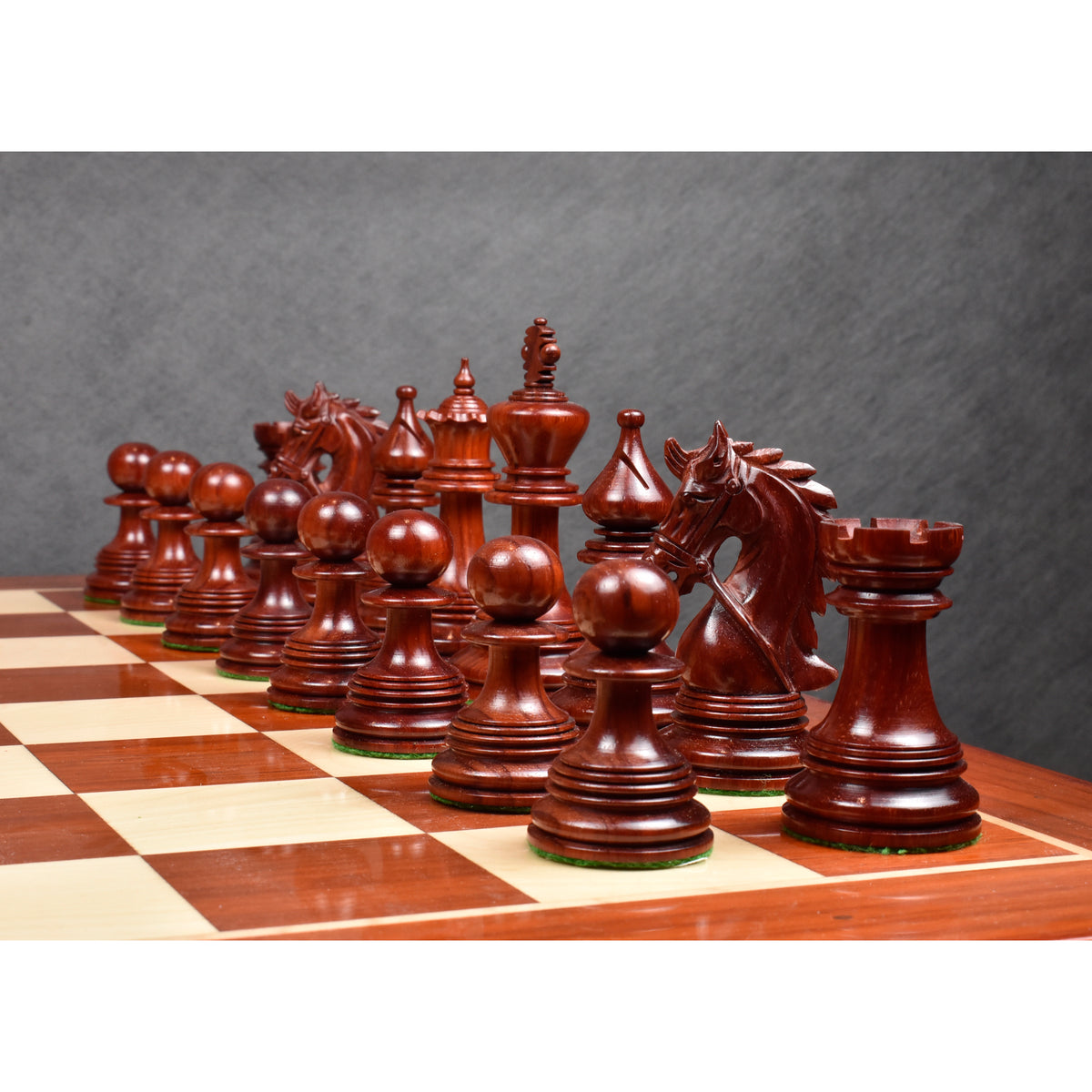 Crimson bud rosewood luxury Staunton chess pieces lined up diagonally across a chessboard.
